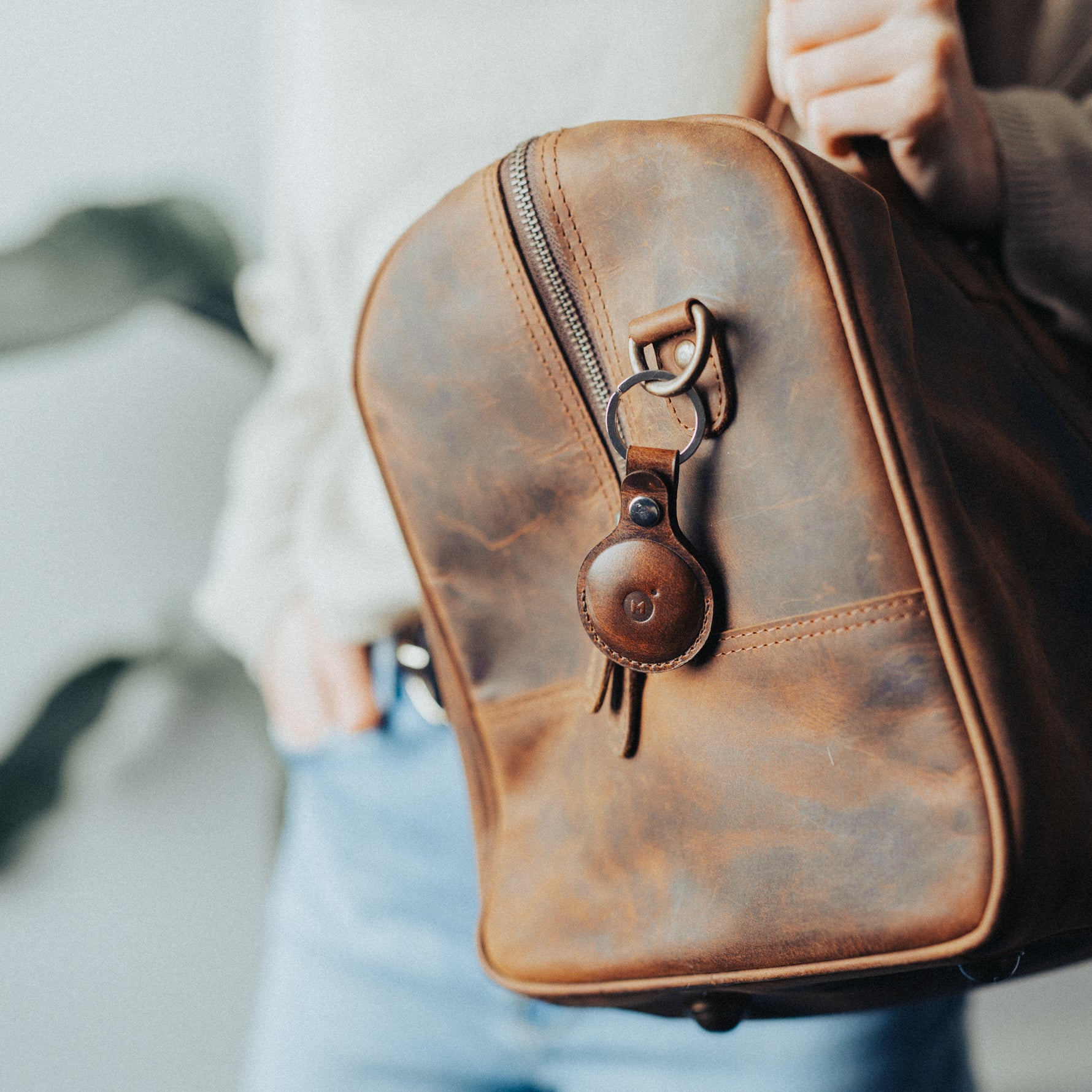 Woman carrying a leather bag with an air tag leather holder