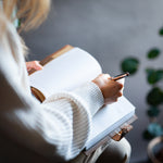 woman writing notes in a lined flower journal