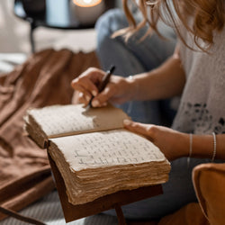 woman writing notes in a deckle edge leather journal