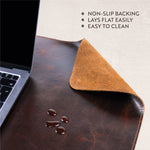 leather desk pad placed under a laptop with drops of water showing that it's easy to clean and has non-slip backing