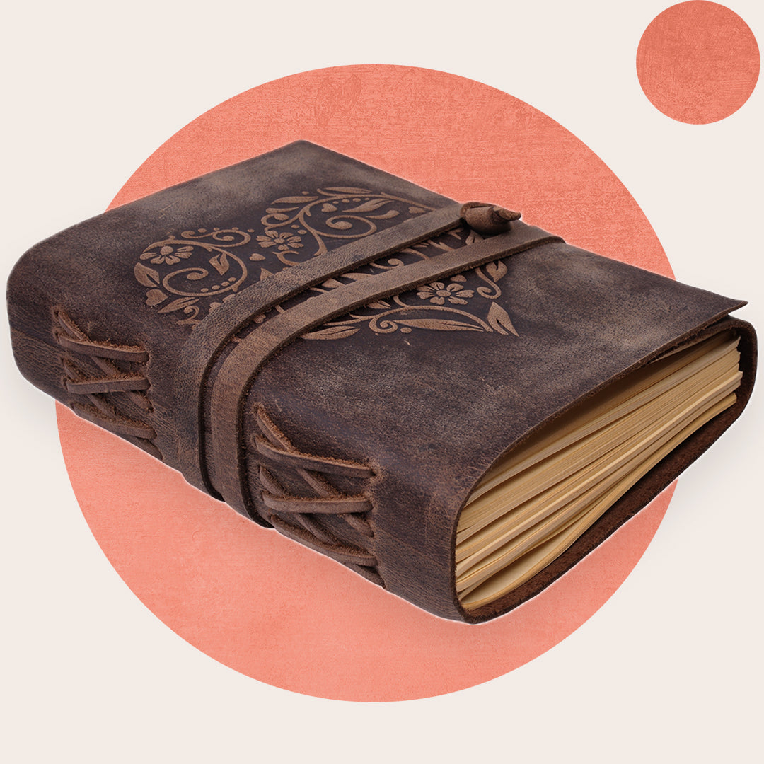 A brown leather journal with a heart embossed cover and a strap closure. The journal appears to be lined and is displayed against a plain background.