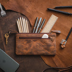 Dark brown leather pencil case with pens and pencils placed on a table