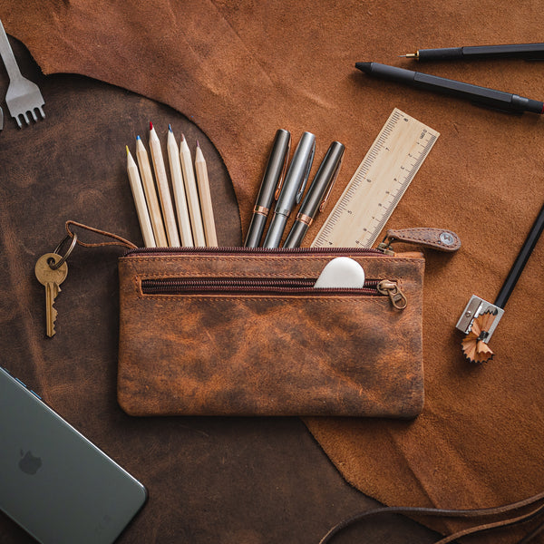 Dark brown leather pencil case with pens and pencils placed on a table