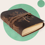 A brown leather journal with a tree of life embossed on the cover, secured with a leather strap.