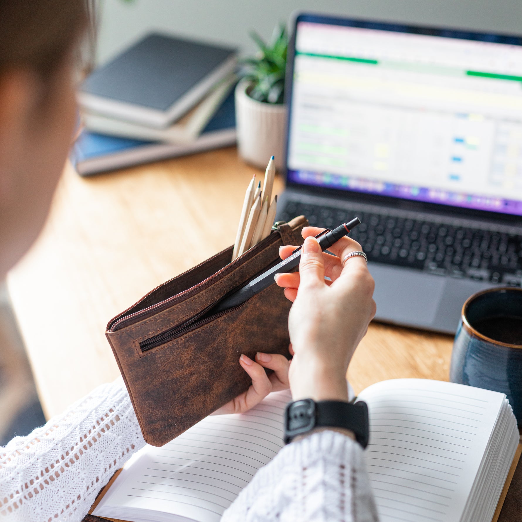 Woman placing a pen in the Moonster leather pencil case