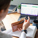 Woman placing a pen in light brown leather pencil case