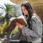 Woman writing in a lined leather journal