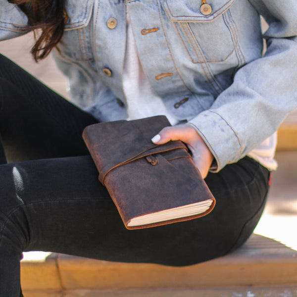Woman holding a lined leather journal