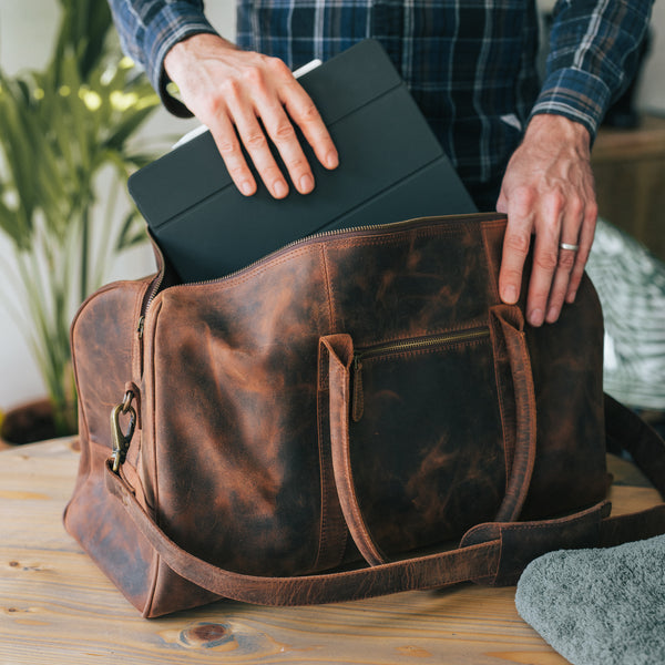 Man putting a pad into a Leather Duffle Bag